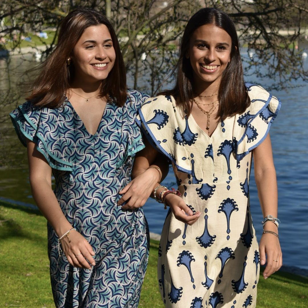 Mujer sonriendo, vestida con un vestido largo de estampado marrón y negro.
